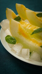 Fototapeta na wymiar ripe melon with crushed ice and mint leaves, cut into pieces and slices