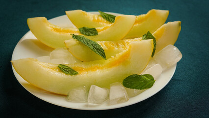 Naklejka na ściany i meble ripe melon with crushed ice and mint leaves, cut into pieces and slices