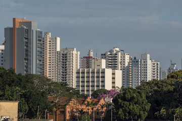 Urban landscape with commercial and residential buildings in the background, trees and old shed in the foreground, Piracicaba SP Brazil.