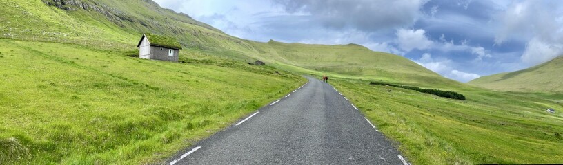 Straight road crossing the green field of Faroe Islands 
