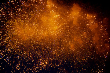 Bright orange glowing fireworks with sparks flying sideways against the night sky. High quality photo