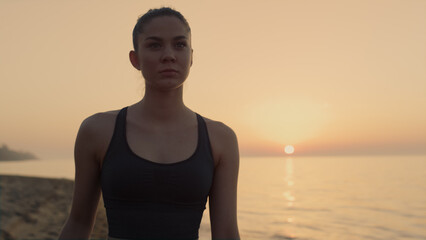 Confident sportswoman walking beach at sunset close up. Girl going near ocean.