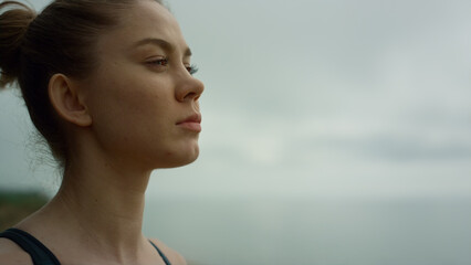 Attractive woman relaxing overcast day close up. Girl meditating on seacoast.