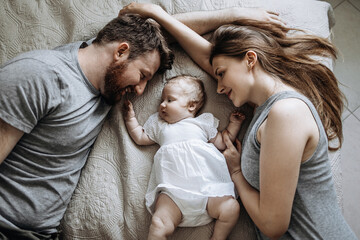 Baby sleeps with daddy and mom on the bed