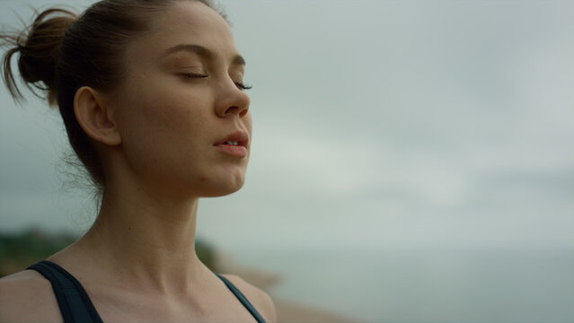 Yogi woman making deep breath meditating on beach. Lady practicing yoga close up