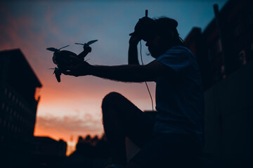 Man pilot sitting silhouette launch quadcopter drone quad urban city