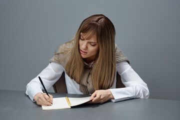 Angry irritated young blonde student lady freelancer in warm sweater hate doing home task at copybook in gray modern home office. Remote Job, Education And Career Profession Concept. Copy space