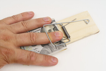 A man's hand fell into a mousetrap with dollar bills for bait.