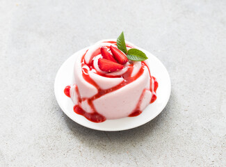 Strawberry cream pudding, Panna Cotta with sauce, in the shape of a rose, on a plate. Light grey...
