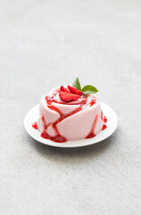 Strawberry cream dessert, Panna Cotta with sauce, in the shape of a rose, on a plate. Light grey background