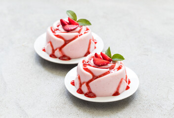 Italian dessert. Strawberry Panna Cotta with sauce, in the shape of a rose, on a plate. Light grey background