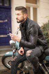 Fototapeta na wymiar smoking handsome macho motorcyclist sit on chopper while being hot and stylish and look to side think about cool and masculine appearance