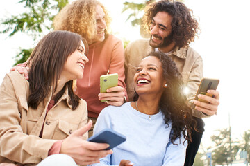 Happy friends using mobile and laughing. Smiling people holding smart phones. Youth culture and technology online concept.