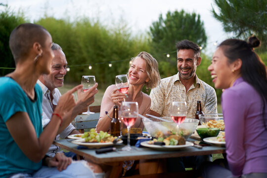 Happy middle-aged men and women toasting healthy food at farm house picnic - Life style concept with cheerful friends having fun together on afternoon relax time