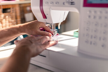 detail of a woman's hands sewing with a sewing machine