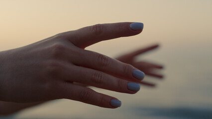 Woman hands reaching forward near ocean close up. Girl practicing yoga asana.