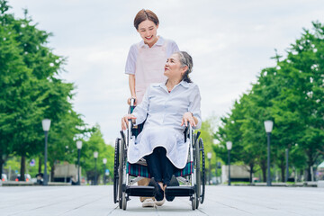 車椅子の女性と介護するエプロン姿の女性
