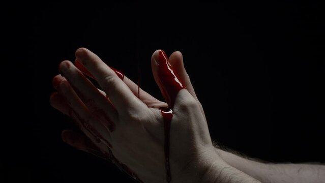 Close-up caucasian male hand covered in blood, crime scene, bloody hand isolated on black background