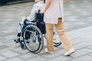車椅子の女性と介護するエプロン姿の女性