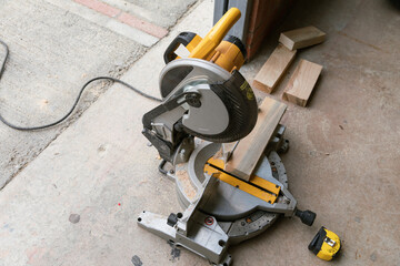 A multi material construction saw with wood on a cement ground. 