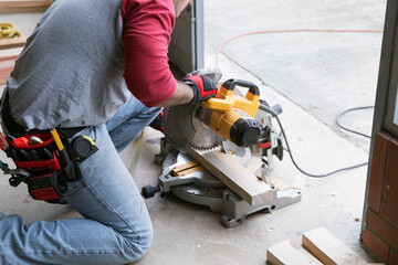 A man sawing wood with a multi material construction saw  on the ground.