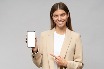 Young business woman holding phone with blank screen and copy space for finance app, pointing to it