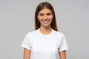Young woman in casual white t-shirt standing isolated on gray background