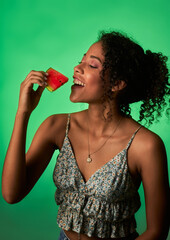 mujer afro latina comiendo sandia en un fondo verde