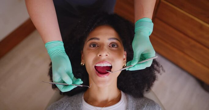 Dentist checking mouth of female patient during a dental appointment from above. African woman having her routine checkup to prevent tooth decay and gum disease. Good oral hygiene means healthy teeth