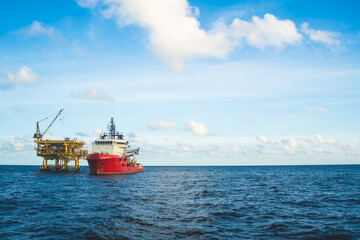 A tugboat anchors near an oil rig at an oil well to transport necessary rigging.