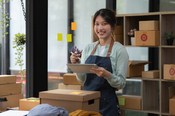 Image of Young asian woman startup freelance with parcel box and talking with customer by computer laptop. Online marketing packing box delivery concept.