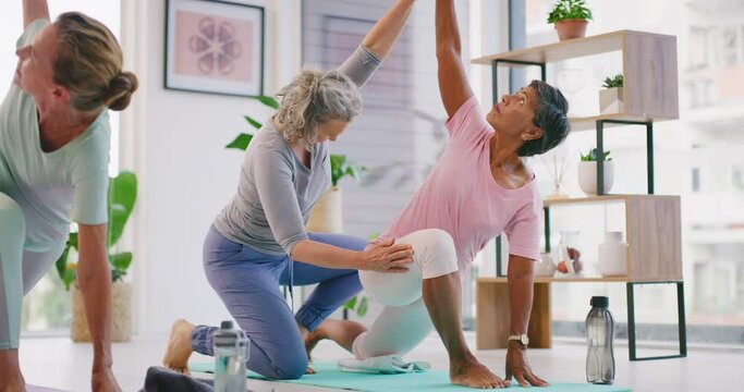Senior yoga instructor teaching beginner poses to mature women in her exercise class. Fit ladies practicing yoga with the help of an instructor in her studio. Living an active and healthy lifestyle