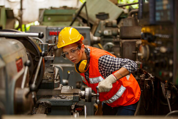 Professional young White female industry engineer worker works in safety uniform with metalwork precision tools, mechanical lathe machines, and spare parts workshop in the steel manufacturing factory.