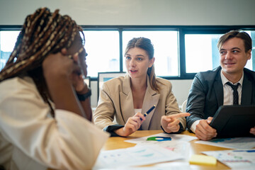 Business people discussing the charts and graphs showing the results of their successful teamwork, multi ethnic business