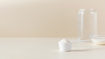 A scoop with hydrolyzed collagen powder on a beige background. The concept of food additives, healthy. Copy space