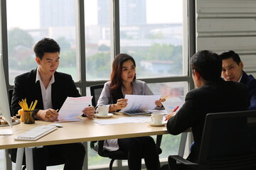 Group of young modern people in smart casual wear communicating and using modern technologies while working in the office