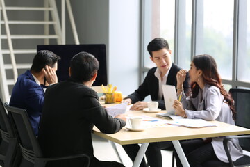 Group of young modern people in smart casual wear communicating and using modern technologies while working in the office