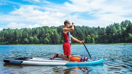 Teenager on a SUP board rakes a wave with an oar. SUP surfing. The concept of an active lifestyle.