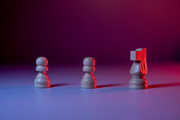 Two pawns and a chess knight arranged on a purple background with lights. © Wacha Studio