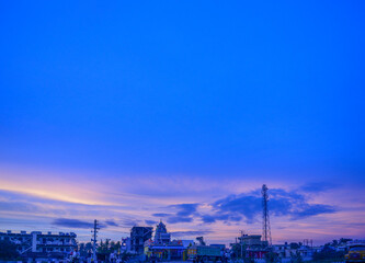 Fototapeta na wymiar Sunrise over a India against a striking blue sky with random buildings in the background. Can be used as a presentation slide.