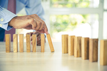 Close-up hand prevent wooden block not falling domino concepts of financial risk management and...