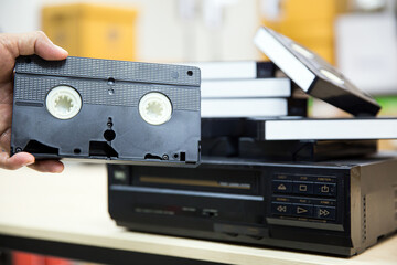 Close-up hand chooses video cassette tape VHS old retro style on video record playback concept of...
