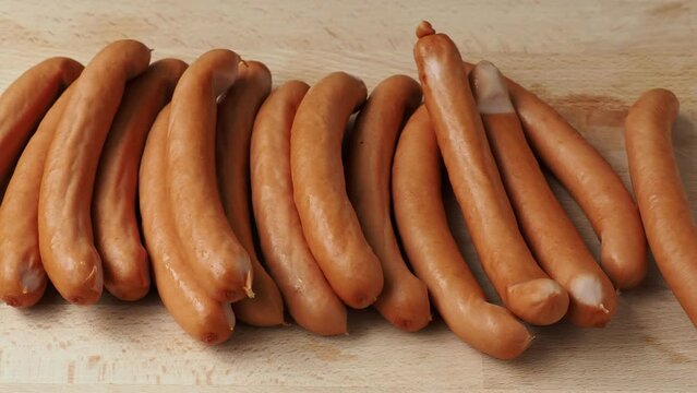 Thin long pork sausages on the wooden cutting board