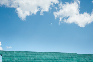Fototapeta na wymiar un bâtiment bleu devant un ciel bleu avec des nuages blancs. Détail d'un building moderne sous un ciel bleu d'été.