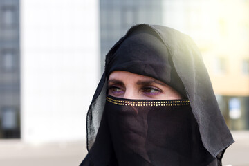 Muslim woman close-up portrait of her face in a black scarf on her head.