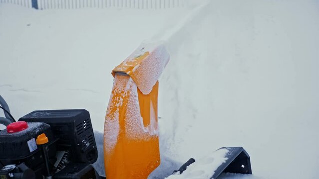 Anonymous uses snow blower to clean road in park, close-up. Powerful snow plough cleans pathway from snowdrifts after heavy snowfall