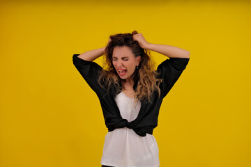 Close-up portrait of a beautiful girl on a yellow background. woman screaming and holding her hair. human emotions