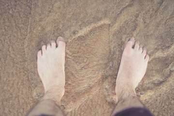 Feet standing in the ocean water