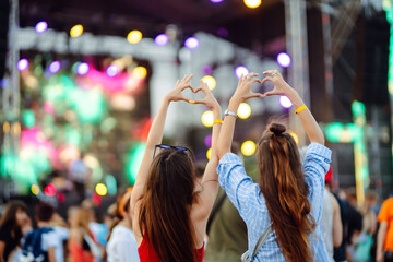 Heart shaped hands at concert, loving the artist and the festival. Music concert with lights and silhouette of people enjoying the concert. - Powered by Adobe