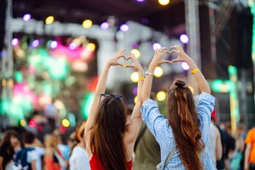 Fotobehang Heart shaped hands at concert, loving the artist and the festival. Music concert with lights and silhouette of people enjoying the concert. © maxbelchenko